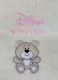 Primo piano di una copertina per neonati beige con ricamo: nome «Diana» in corsivo rosa e data di nascita «01.03.2021». In basso, applicazione a forma di orsacchiotto beige sorridente con zampe bianche.
