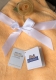 Morbida copertina per neonati arancione con fiocco in raso bianco e delicata rosa in tessuto giallo chiaro. Sulla copertina sono appesi due cartellini: il certificato Oeko-Tex Standard 100 e l'etichetta KiddiBaby. Sono garanzia di sicurezza e comfort.